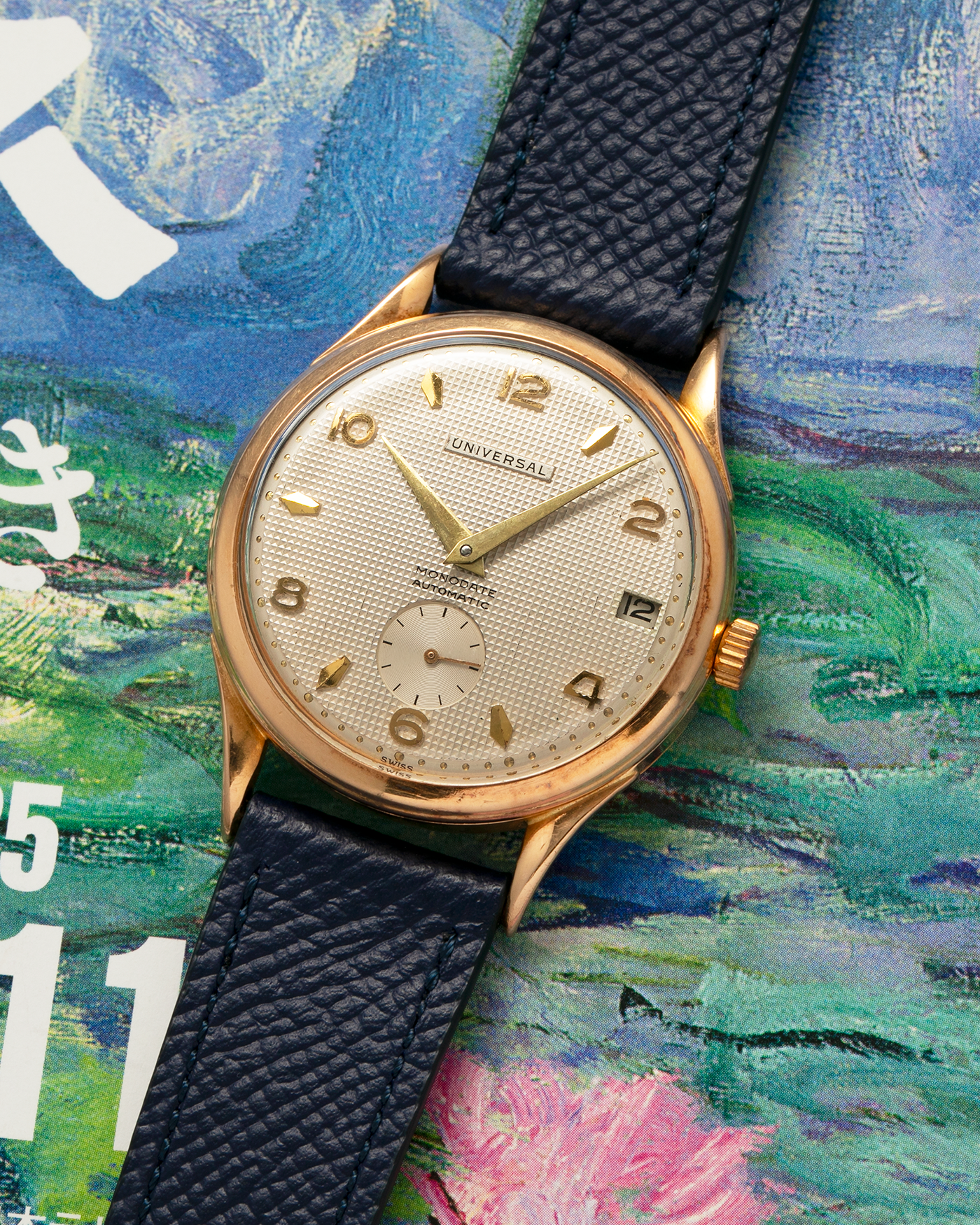 Brand: Universal Genève 
Year: 1950s
Material: 18-carat Yellow Gold
Movement: Universal Genève Cal. 138C, Bumper Self-Winding
Case Dimensions: 35mm x 10.5mm (Lug-to-Lug 43mm)
Lug Width: 18mm
Strap: Nostime Dark Navy Textured Calf Leather Strap 