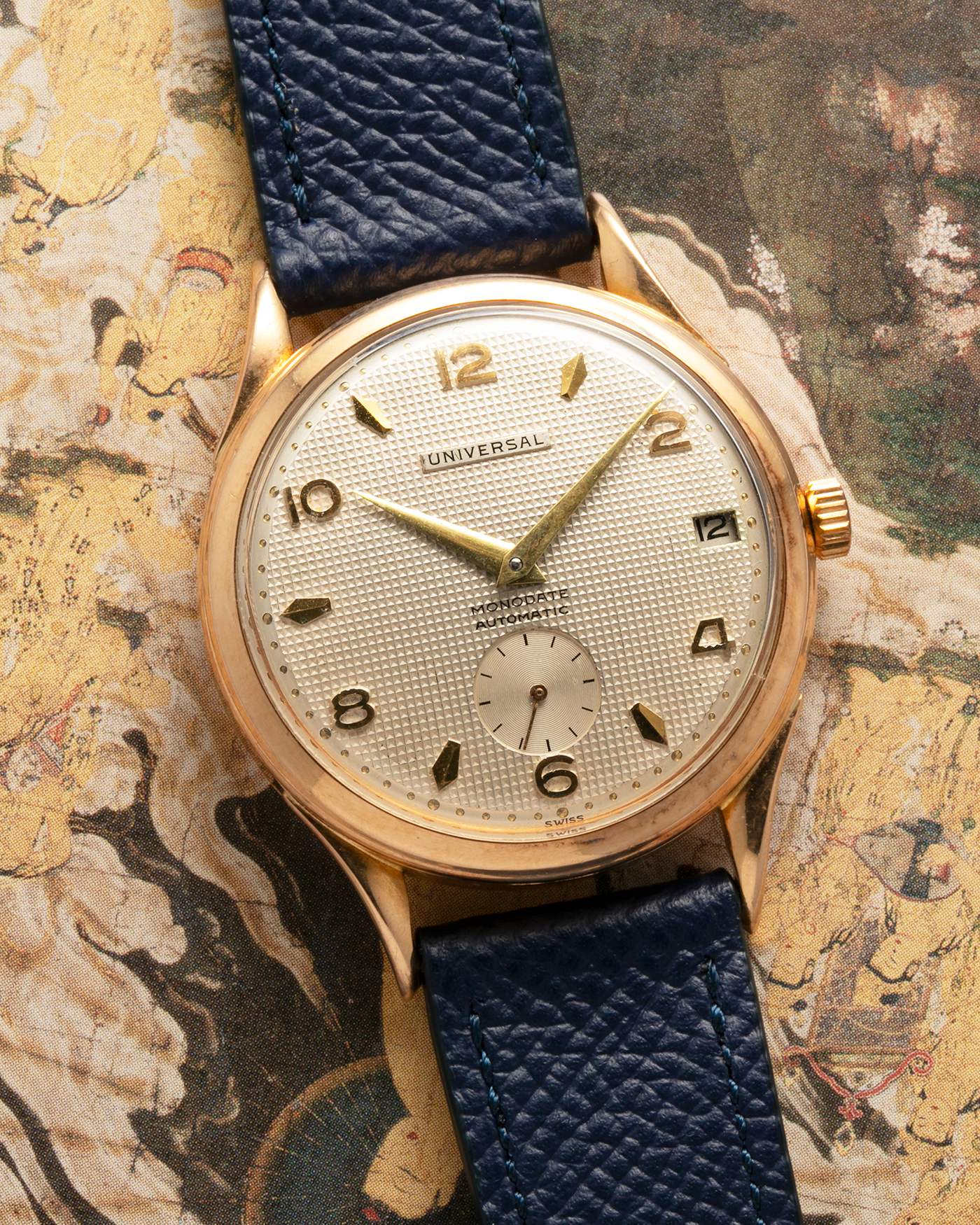 Brand: Universal Genève 
Year: 1950s
Material: 18-carat Yellow Gold
Movement: Universal Genève Cal. 138C, Bumper Self-Winding
Case Dimensions: 35mm x 10.5mm (Lug-to-Lug 43mm)
Lug Width: 18mm
Strap: Nostime Dark Navy Textured Calf Leather Strap 